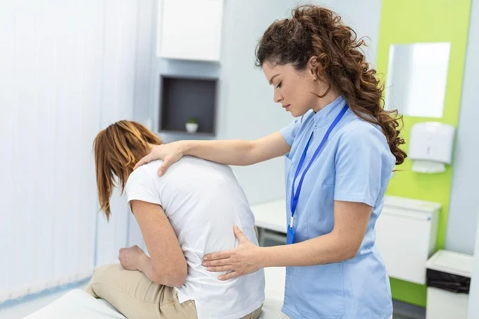 Chiropractor examining a patient's back for pain relief through hands-on therapy