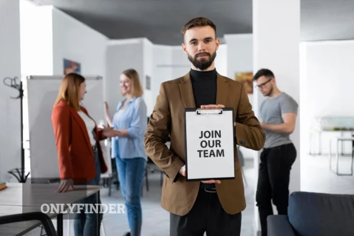 Professional holding a 'Join Our Team' sign in a modern office, promoting a productive workplace and the importance of running a business.