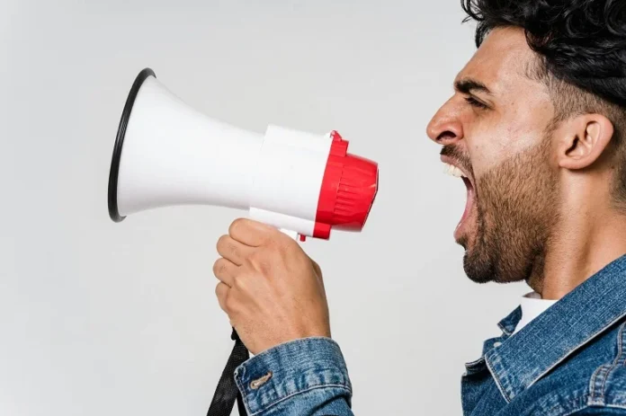 Man shouting into a megaphone highlighting the need for Addictive Sound acoustic panels to improve sound quality.