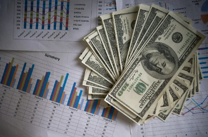 Tips for Saving Your Business Money A stack of hundred-dollar bills placed on financial charts and graphs, symbolizing effective strategies for saving your business money.