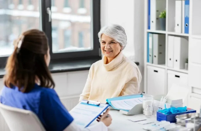Elderly woman discussing assisted living transition with a healthcare professional in a bright office.