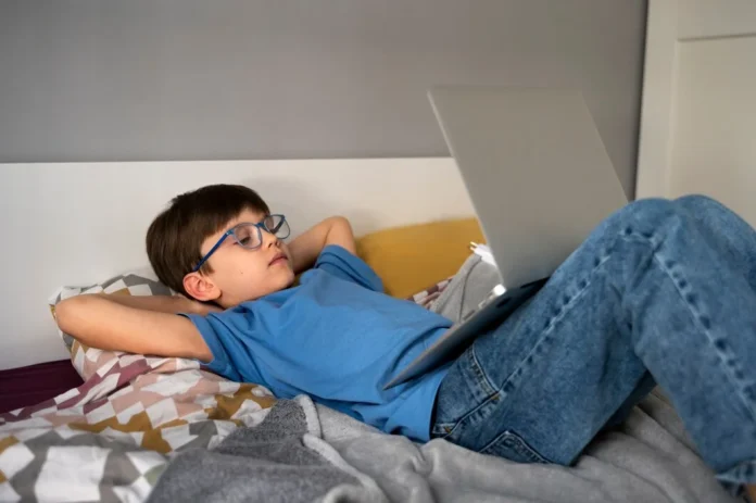 Teen Sleep Habits - Why Good Sleep is Important for Teenagers Teen lying on bed using laptop late at night, showing unhealthy teen sleep habits.